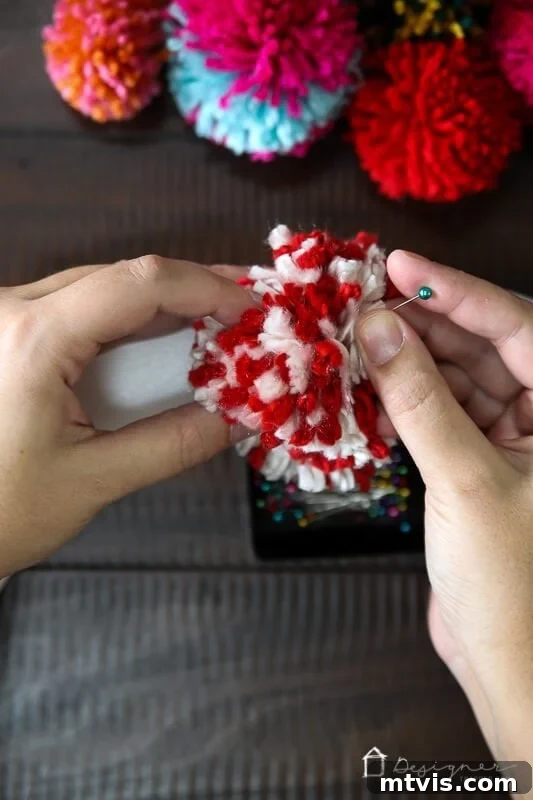 Fluffy Pom Pom Wreath Craft 7 Pinning colorful pom poms onto a foam wreath form for DIY project