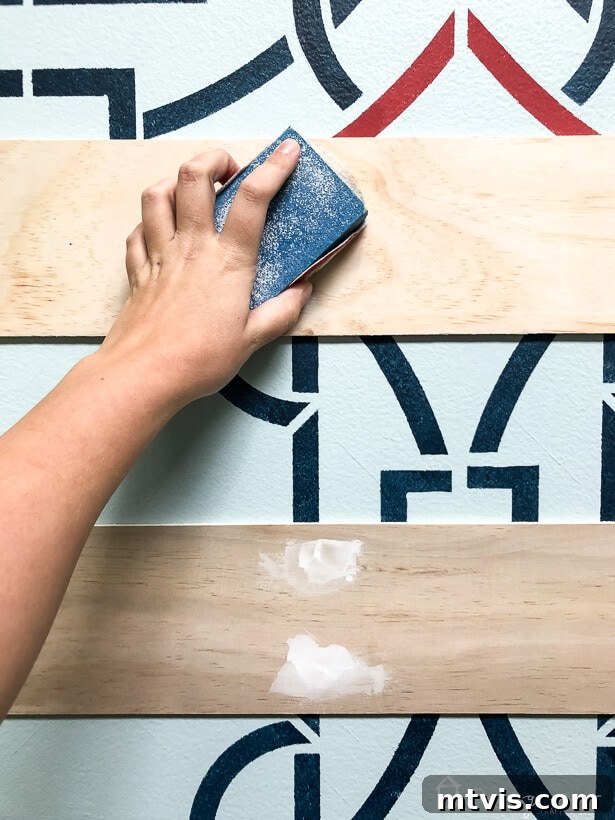 Sanding patched nail holes on a newly installed plank wall for a smooth finish.