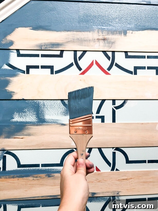 Painting the newly installed modern plank wall with Behr's Color of the Year, Blueprint S470-5, for a striking finish.