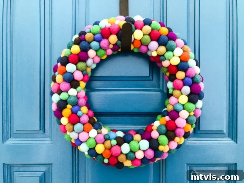 Vibrant Felt Ball Wreath Project 11 The finished colorful DIY felt ball wreath beautifully displayed on a vibrant blue door, creating a cheerful and inviting entrance.