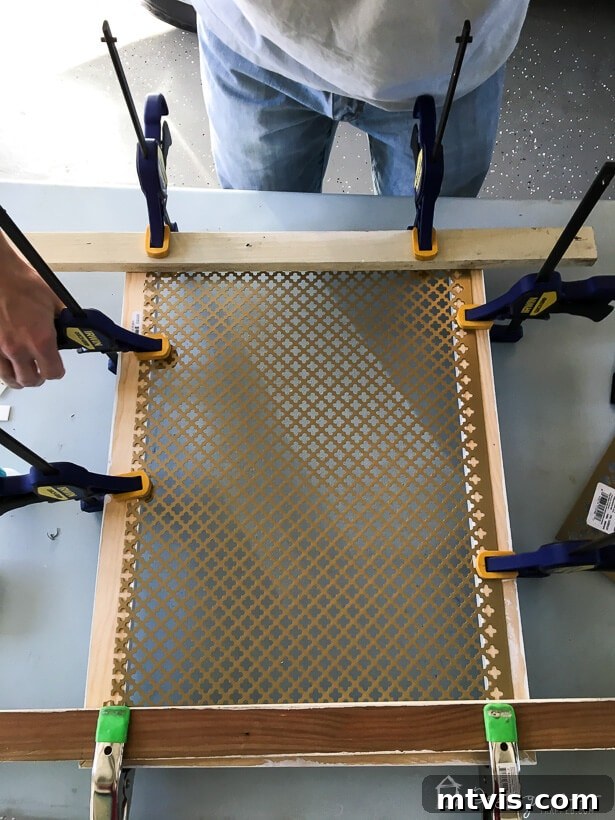 Stylish DIY Vent Cover Made Simple 7 Assembling a DIY vent cover by gluing a metal sheet to a wooden frame, secured with clamps.