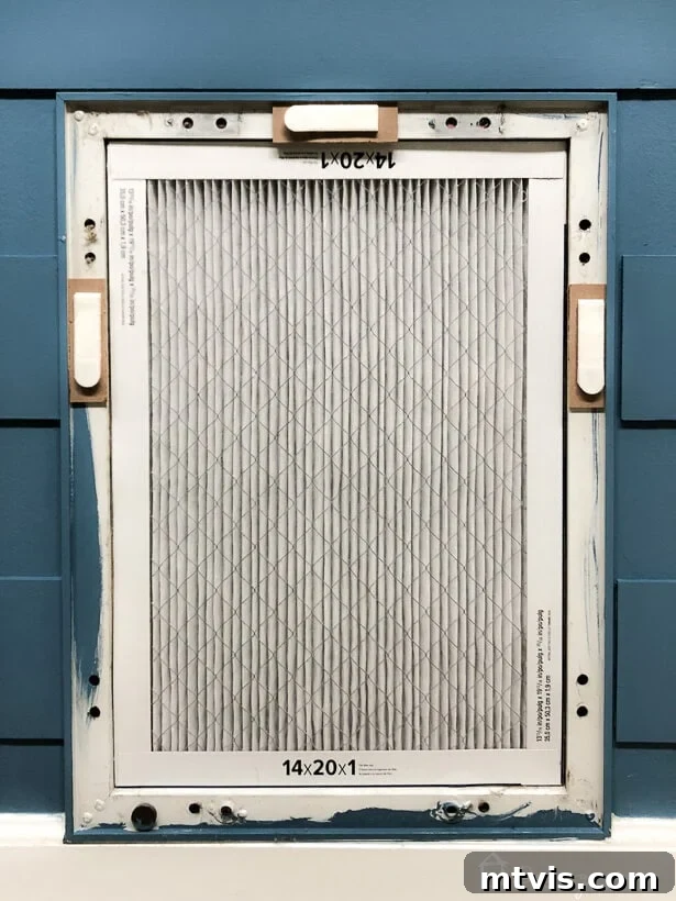 Stylish DIY Vent Cover Made Simple 10 Applying Command picture hanging strips to the back of a DIY air vent cover for installation.