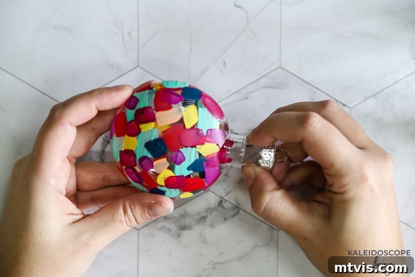Craft Your Own Hand-Painted Christmas Ornaments 7 Assembling a newly painted plastic ornament by reattaching the hanger.