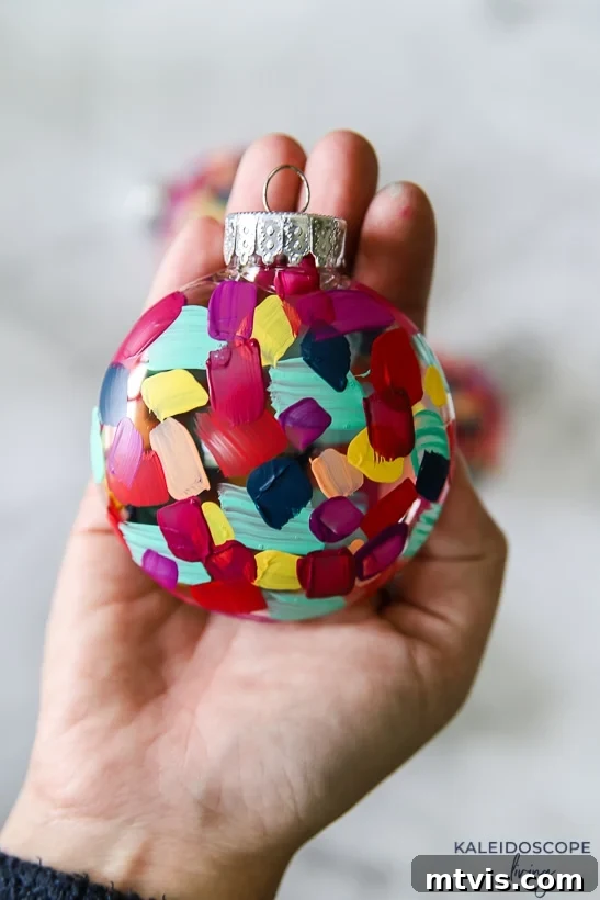 Craft Your Own Hand-Painted Christmas Ornaments 8 A finished colorful hand painted plastic ornament held gently in a hand.