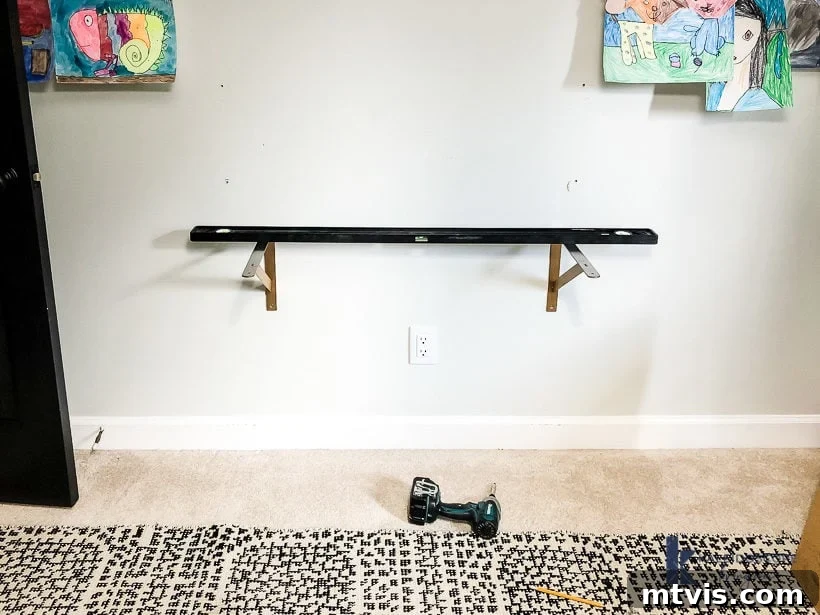 Kendi Masanı Yapmak Çocuk Oyuncağı 4 Measuring and leveling wall brackets for a DIY floating desk installation, ensuring perfect horizontal alignment.