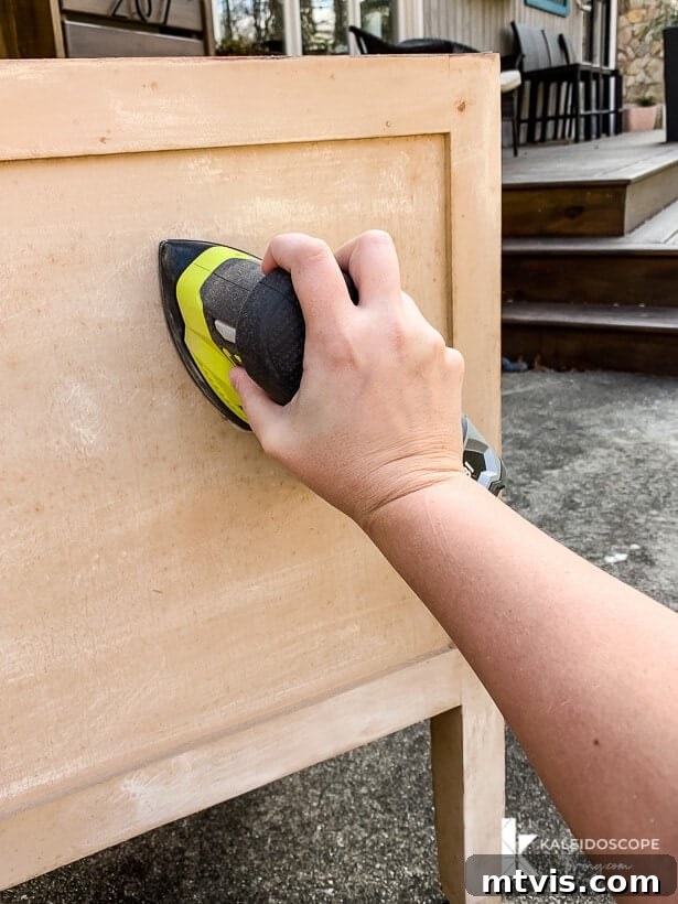 Chalk Paint Secrets: Your Complete Guide to Furniture Makeovers 3 Sanding a piece of old wood furniture to prepare it for painting, highlighting the importance of surface preparation for a durable finish. Using 80-grit sandpaper for initial smoothing. Behr Chalk Decorative Paint process.