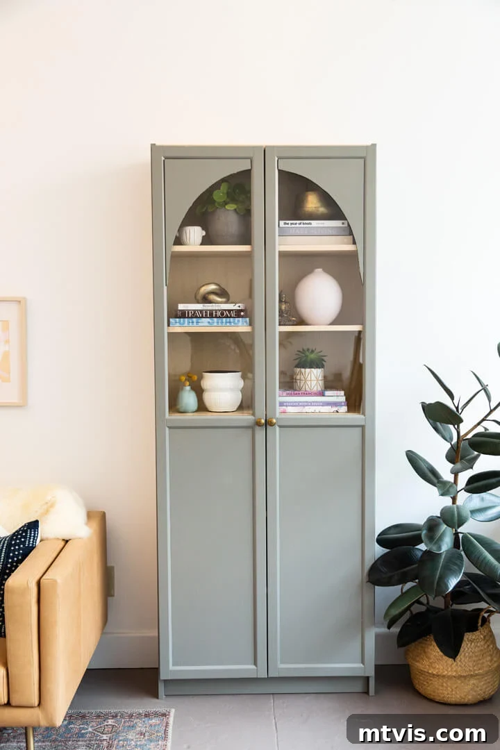 IKEA Smart Hacks: Custom Built-Ins and Bookshelf Upgrades 7 An IKEA Billy bookcase turned into a DIY arched cabinet painted light sage green.
