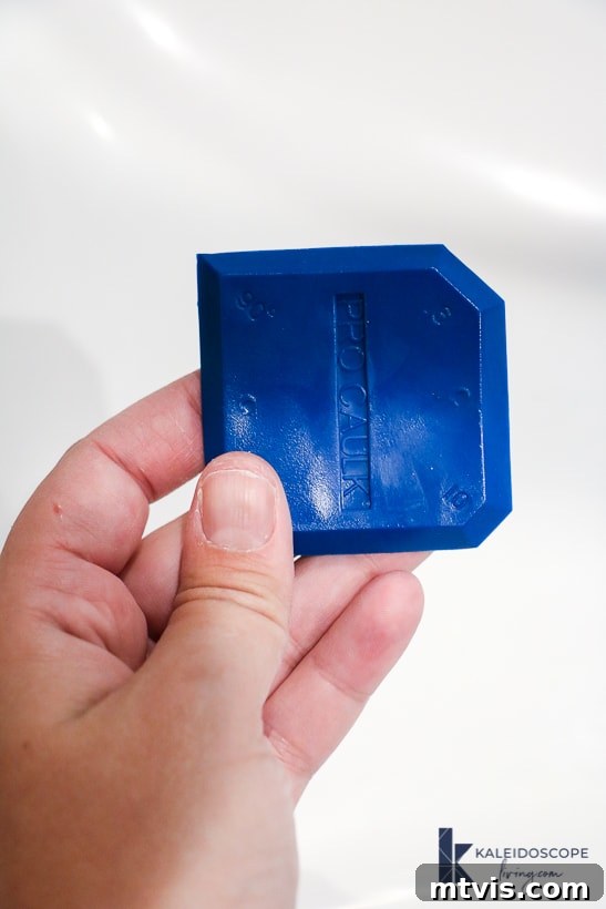 Caulking Made Easy A Beginner's Guide 7 Fingers hold up a blue caulk-smoothing tool.