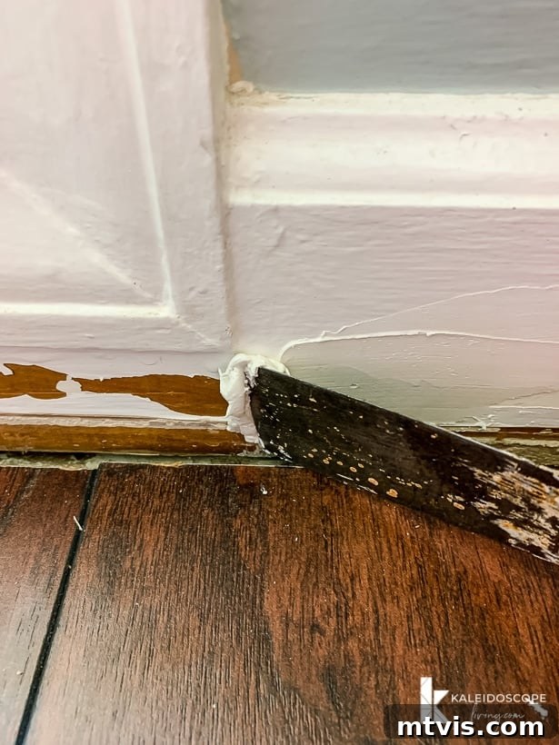 applying DAP Alex Plus Spackling to a damaged baseboard