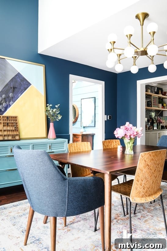 Eclectic dining room with a mix of mid-century modern table, blue chairs, and restored vintage side chairs
