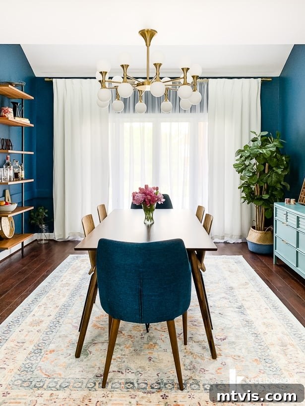 A beautifully decorated navy blue eclectic dining room with mid-century modern touches