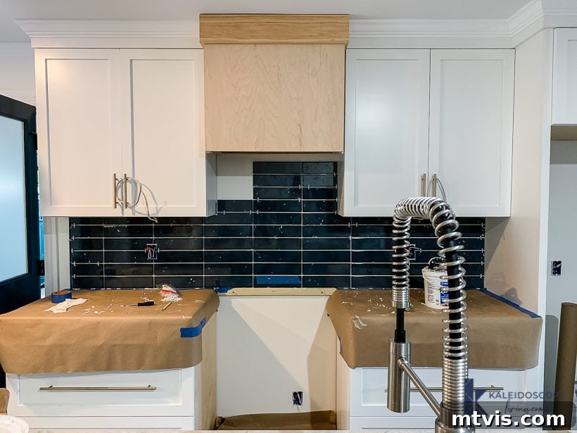 Wood and White Concrete: A DIY Range Hood Transformation 4 Kitchen showing dark blue tile backsplash nearing completion, with the basic plywood frame of the range hood ready for DIY finishing