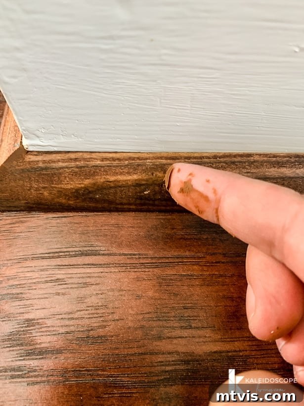 DIY Quarter Round Molding Installation 11 A finger spreads Mohawk Patchal Putty over nail holes in quarter round molding, blending it seamlessly.