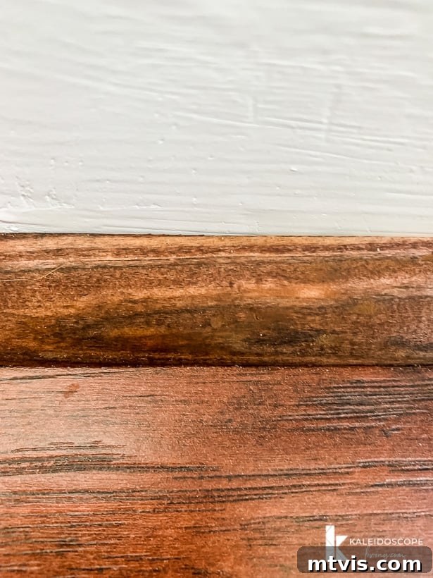 DIY Quarter Round Molding Installation 12 A close-up of stained quarter round molding against a wood floor showing that nail holes are covered by near invisible putty, demonstrating a professional finish.