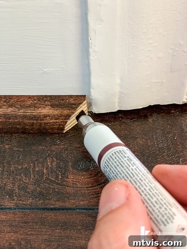 DIY Quarter Round Molding Installation 8 A Mohawk Pro-Mark marker is being used to color the end of quarter round molding installed on a white wall. The text reads, 'KaleidoscopeLiving.com.'