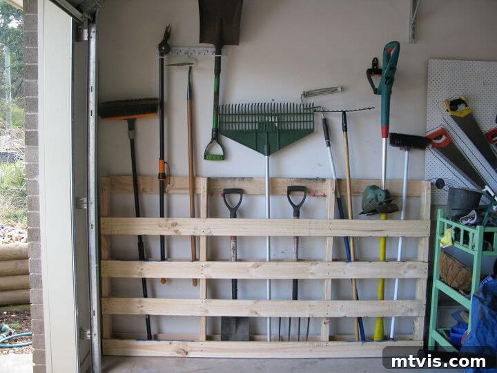 DIY pallet tool organizer in a garage for shovels, rakes, and various yard tools, maximizing wall space.