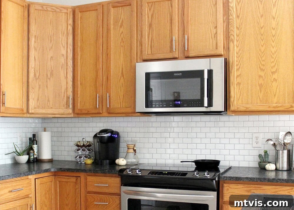 Budget DIY Kitchen Backsplash Makeovers 15 A simple peel-and-stick subway tile backsplash instantly elevates and modernizes brown cupboards in this kitchen update.