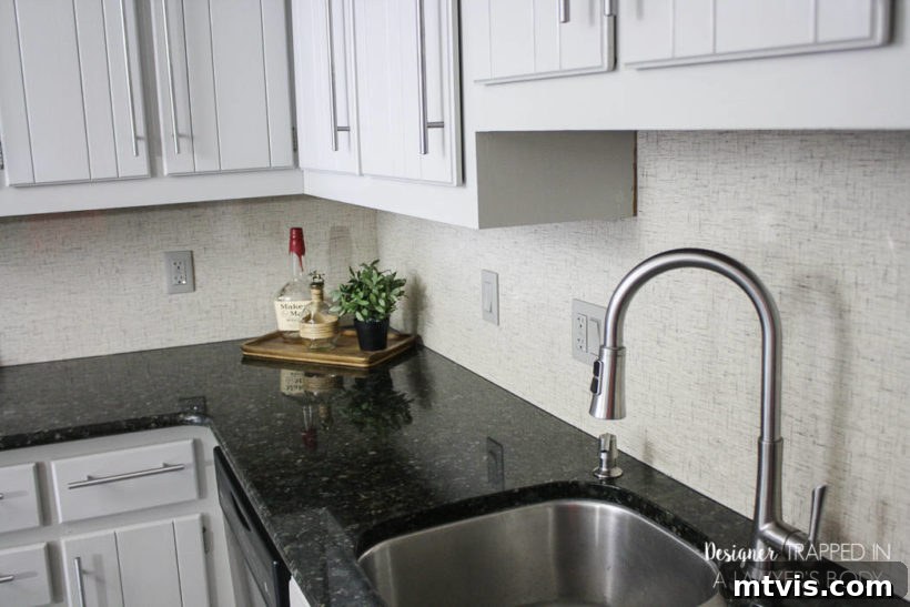 Budget DIY Kitchen Backsplash Makeovers 4 A pristine white kitchen, complete with dark countertops, is beautifully accented by a simple, elegant white Formica backsplash.