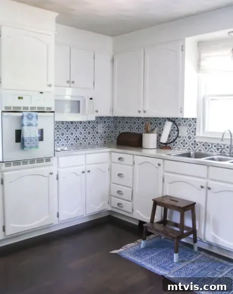 Budget DIY Kitchen Backsplash Makeovers 9 A charming blue and white kitchen receives a delightful pop of color from a beautifully painted backsplash designed to resemble antique tiles.