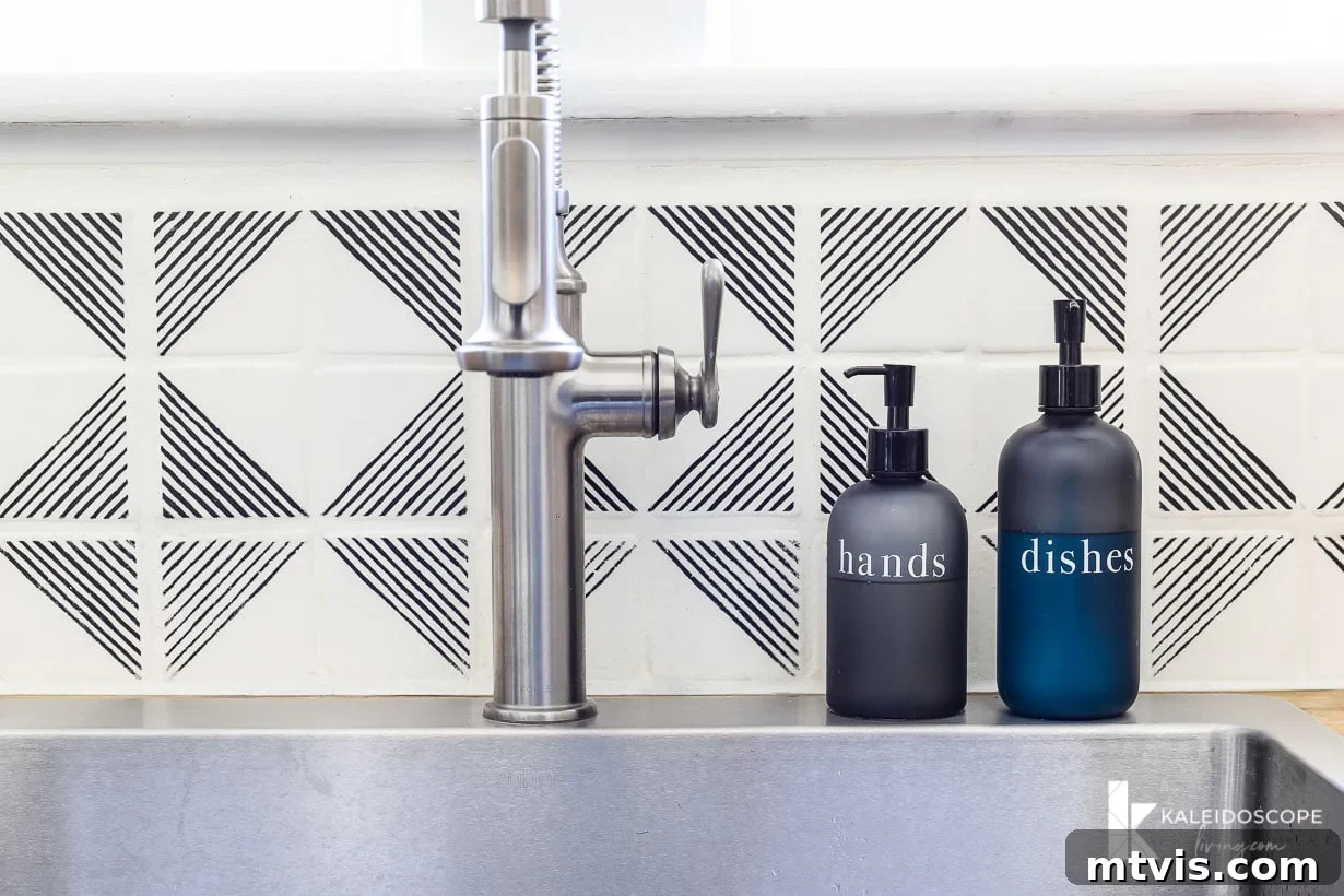 DIY Kitchen Transformation Under One Thousand 19 A close-up of a faucet and a white and black geographic tile stenciled backsplash. Two pump bottles to the right of the sink say "hands" and "dishes." "KaleidoscopeLiving.com" is written in the lower right corner.