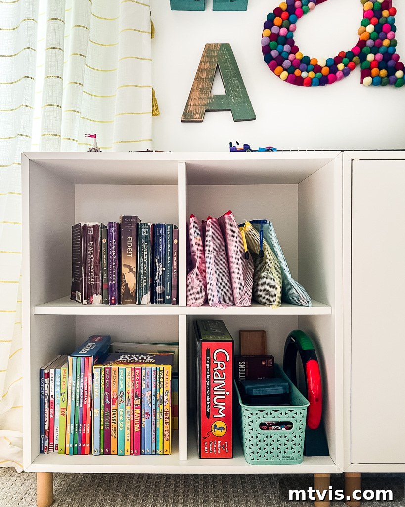 Transform Your Playroom: Simple Storage for a Clutter-Free Zone 6 A bookshelf organized with zippered pouches for board games, labeled and neatly arranged, illustrating an innovative playroom storage idea.