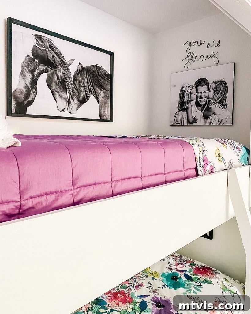The Big Reveal: Avery's Bespoke Bunk Bed Room 7 The top of this bedroom's built-in bunk beds has a pink duvet and the wall has a picture of horses, a canvas print of a father with two daughters, and a sign that says,