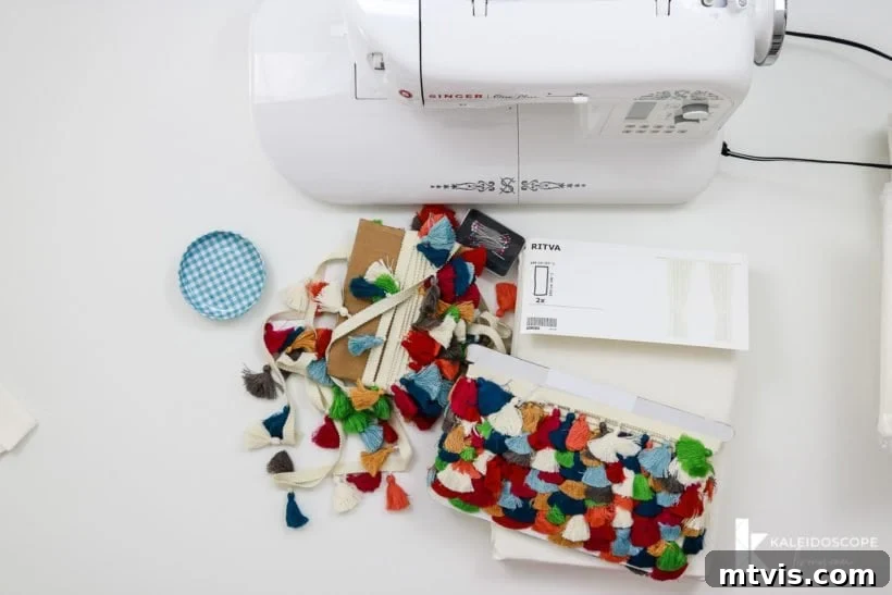 A sewing machine, colorful tassel trim, and fabric glue laid out with curtain panels, ready for the DIY tassel curtain project.