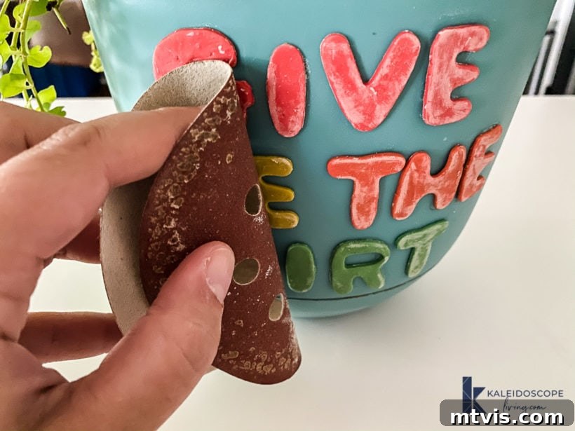 Beyond Basic Pots Polymer Clay Decorating with a Touch of Humor 9 Optional step: Lightly sanding a polymer clay decoration on a plant pot to smooth the surface.