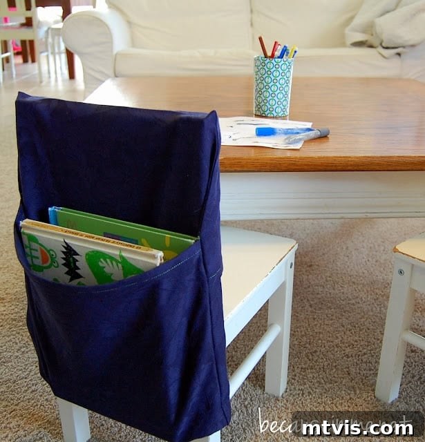 Genius Homeschool Organization Hacks 7 A handcrafted blue schoolbook organizer neatly hangs from the back of a white chair, positioned in front of a table, demonstrating practical daily storage.