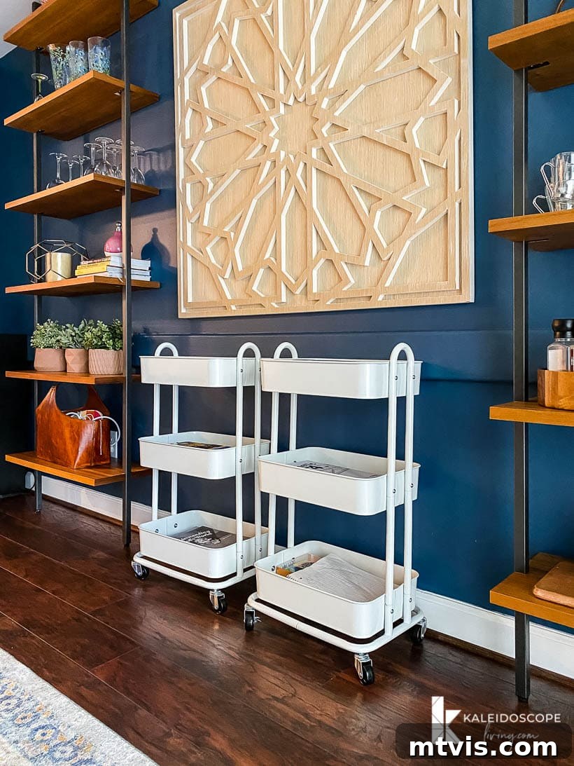 Genius Homeschool Organization Hacks 3 Homeschooling organization in a dining room, featuring mobile utility carts neatly arranged against a blue wall between tall shelves, creating a functional yet adaptable learning zone.