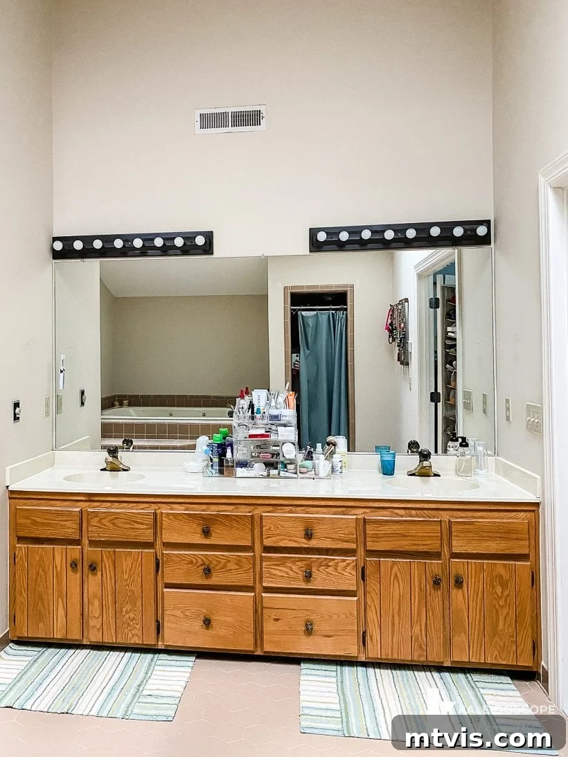 Master Bathroom Remodel on a Budget The Big Reveal 4 outdated wood vanity and lights - Close-up of the old wood vanity, counter, and light fixtures in the master bathroom pre-makeover.