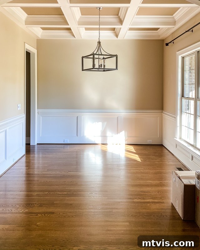 Step Inside Our Navy Blue Dining Room 2 A "before" image of a traditional dining room. It features beige walls, a coffered ceiling, and white wainscoting, awaiting its transformation into a modern navy-blue dining room.