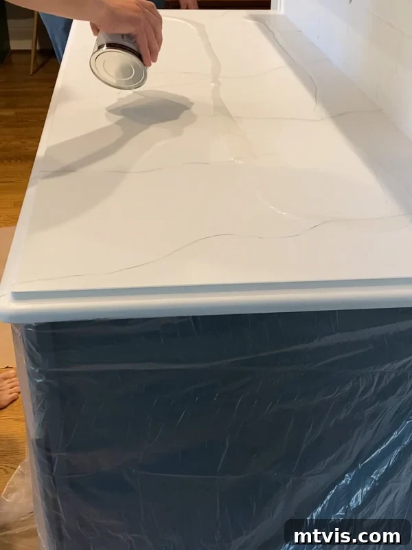 Paint Your Countertops Like a Pro: Essential Tips for a Flawless Finish 16 pouring epoxy resin topcoat on painted kitchen countertops by Tasha Agruso of Kaleidoscope Living
