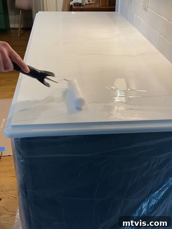 Paint Your Countertops Like a Pro: Essential Tips for a Flawless Finish 17 spreading epoxy resin topcoat on painted kitchen countertops by Tasha Agruso of Kaleidoscope Living