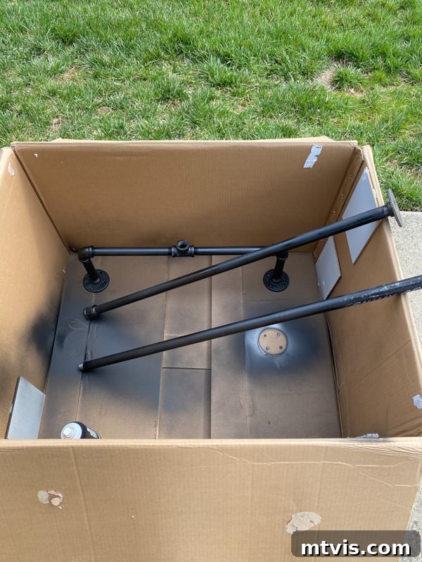 Build Your Own Outdoor Chandelier 6 Pieces of gas pipe laid out in a box, ready for spray painting to prevent overspray for the DIY chandelier.