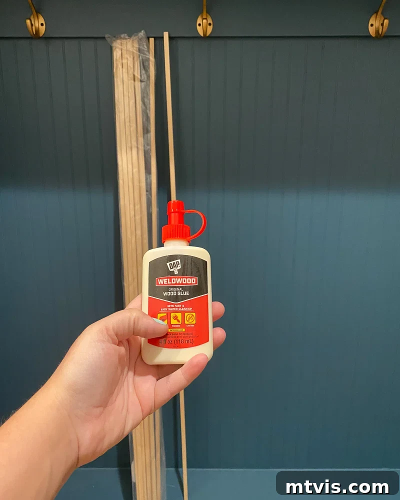Modern Wood Slat Wall Transformation 6 Detailed view of applying wood glue to a dowel during DIY slat wall installation
