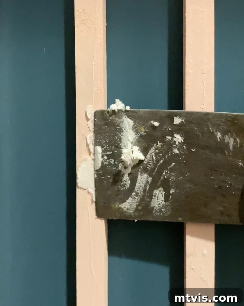 Modern Wood Slat Wall Transformation 9 Expertly filling nail holes with spackle for a smooth, finished look on a wood slat accent wall
