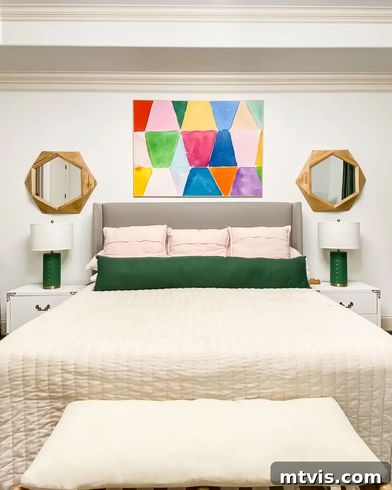 A primary bedroom with bold colorful art, matching white campaign dressers as nightstands, and elegant lamps.