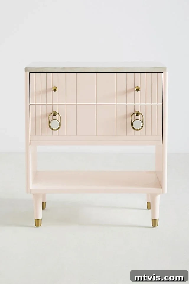 A delicate light pink bedside table with elegant gold accents and a practical bottom shelf.