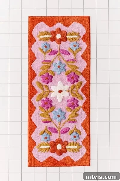 Splash of Style: Top Bath Mats for Bright Bathrooms 6 A vibrant rectangular bath mat featuring a folk floral pattern with red, white, blue, purple, and orange flowers set against a warm pink and rust background. Positioned on a tiled floor, this mat is highlighted as a favorite runner and an excellent choice for adding color and style to any bathroom.