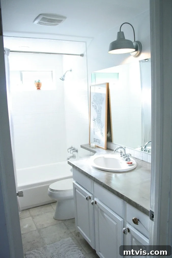 Give Your Shower Tiles a Fresh White Look 5 A bathroom with shower tiles and tub after being painted white for a budget-friendly update.