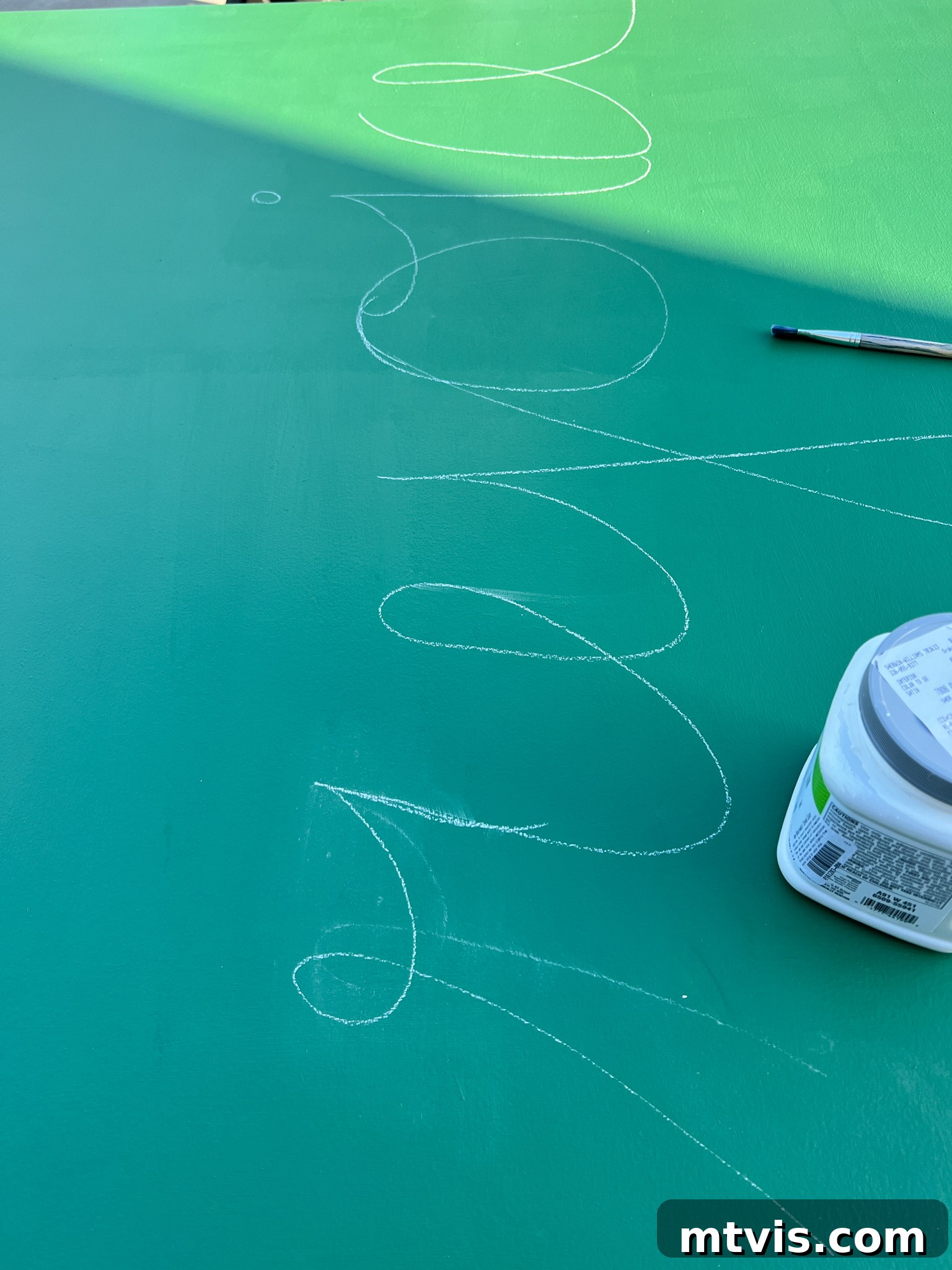 Chalk sketch of the word 'Rejoice' on painted green plywood for light-up art