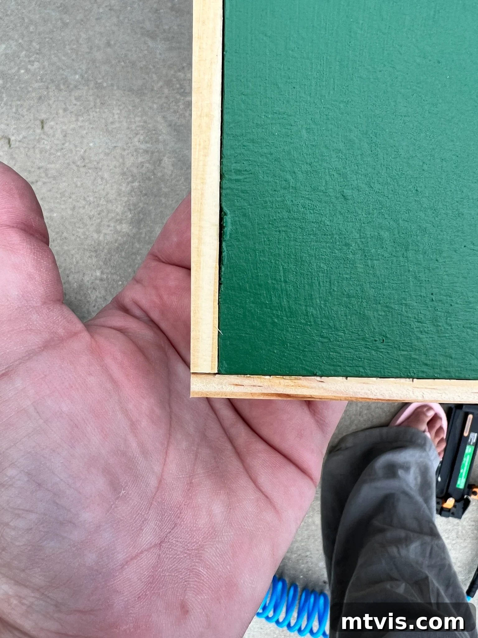 Wood lattice strips being attached to frame the painted plywood art