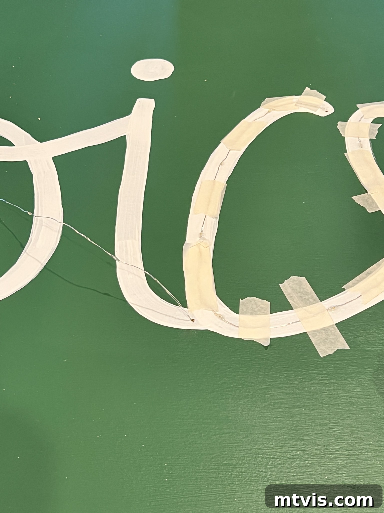 Attaching dewdrop lights to the painted design using clear glue and masking tape