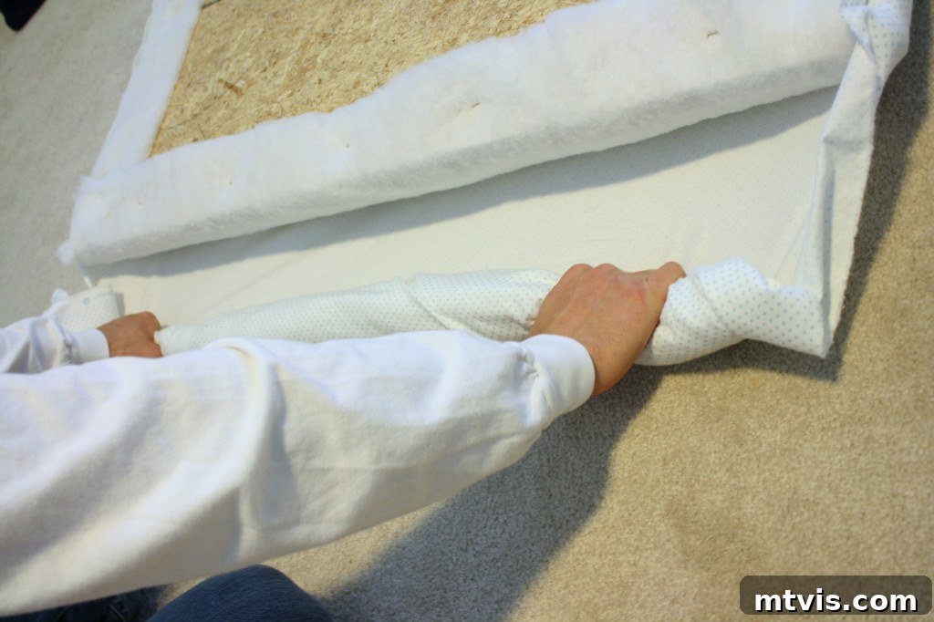 Build Your Upholstered Headboard in an Afternoon 10 Securing the chosen fabric to the headboard base with a staple gun, pulling it taut for a smooth finish.