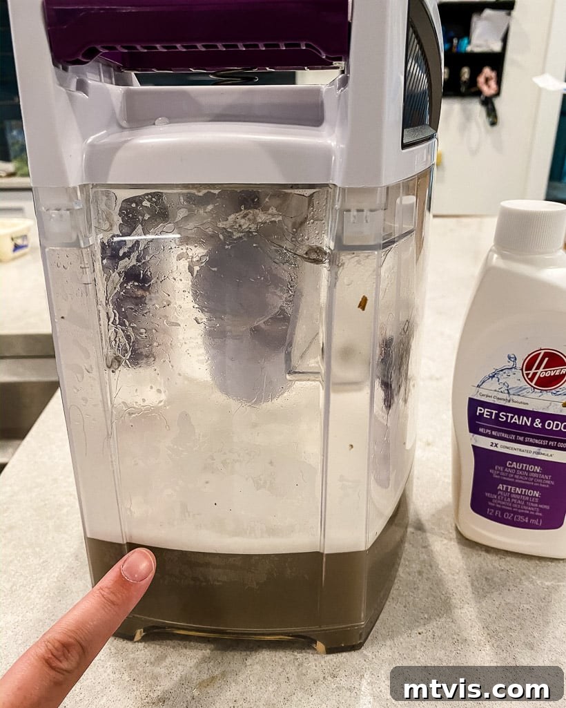 Image showing dirty water collected in a Hoover carpet cleaner after cleaning a rug, demonstrating the machine's efficacy.