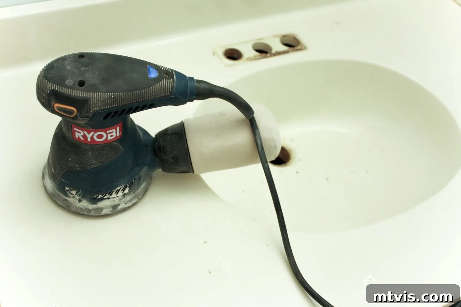 Effortless DIY Concrete Vanity and Sink No Forms No Heavy Lifting 3 A person scuff-sanding a cultured marble bathroom vanity and sink to prepare it for a concrete overlay, highlighting the importance of surface prep for adhesion.