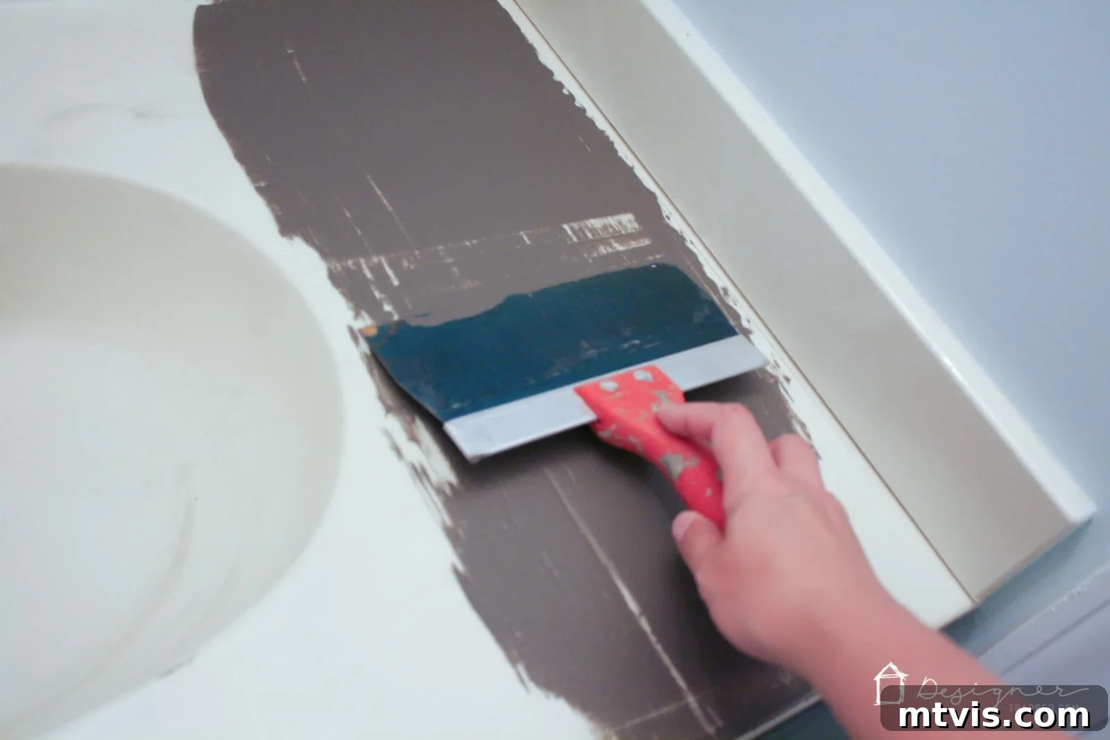 Effortless DIY Concrete Vanity and Sink No Forms No Heavy Lifting 5 A person applying a thin, initial coat of concrete overlay to a bathroom vanity countertop and backsplash, demonstrating the technique for the first layer.
