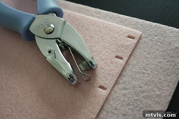 Felt Doll Magic: Create Your Own Playtime Friends 8 A hand punch creates uniform holes along the marked edge of a felt piece, preparing the book covers for stitching.