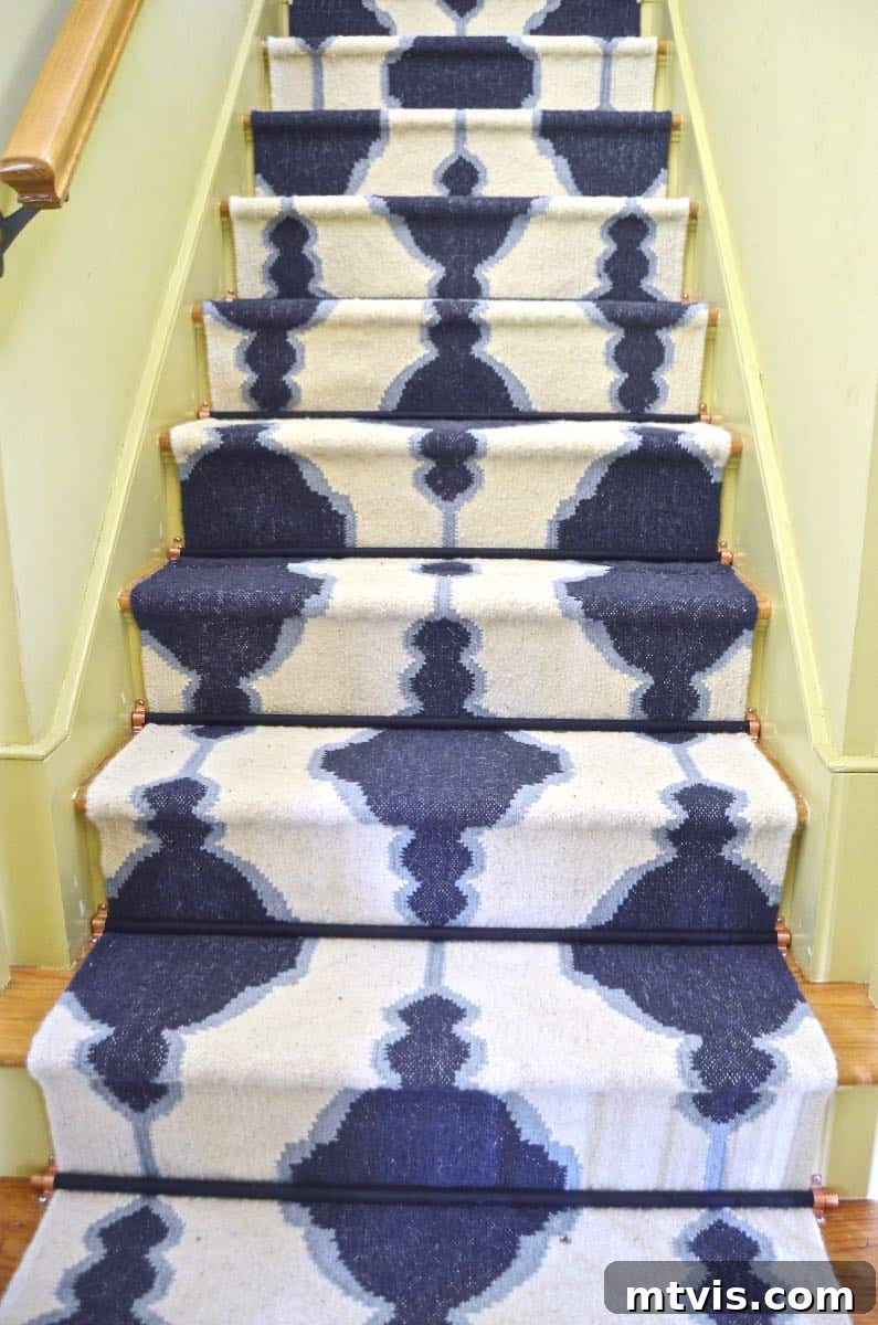 Elevate Your Entryway: Creative Stair Runner Designs 16 A budget-friendly blue and white graphic stair rug beautifully contrasted with yellow walls and accented by elegant black stair rods, exemplifying smart DIY design.
